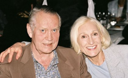 A man and woman sit side by side, smiling.